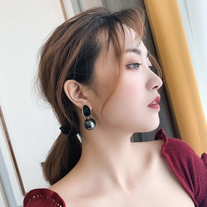 Détail de boucles d'oreilles pendantes avec émail noir et perle grise sur mannequin