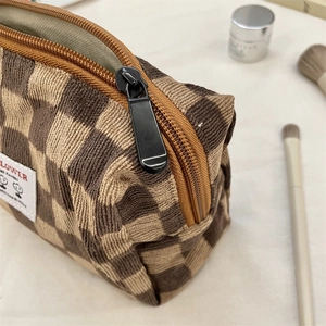 Detail of corduroy checkerboard cosmetic bag with metal zipper and LOWER logo tag