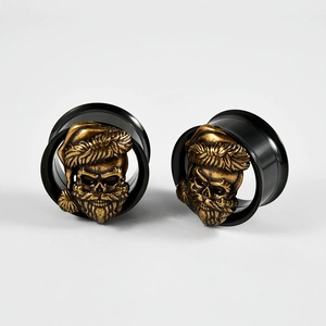 Detail of black double flared ear plugs with golden skull and Santa hat relief design