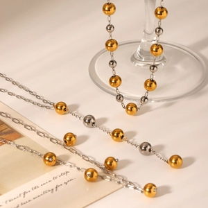Close-up of mixed gold and silver beaded chain necklaces on an elegant card