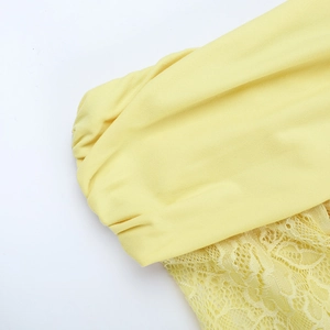 Detail of yellow off-shoulder dress with lace splicing and pleated fabric texture