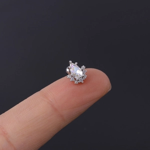 Close-up of small teardrop crystal earring with tiny diamonds held on a fingertip