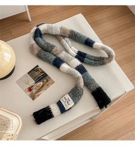 Detail of colorful striped knitted scarf with soft texture and brand label on white table