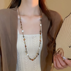 Dettaglio della collana con nappine vintage e perline colorate su catena d'oro
