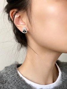 Close-up of gourd-shaped earrings with black gemstone and crystals on ear lobe