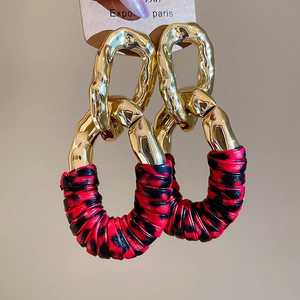 Close-up of golden metal links and red leopard print leather wrap on stylish earrings