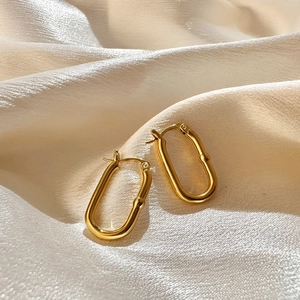 Detailed close-up of 18K gold-plated U-shaped earrings on elegant champagne silk fabric