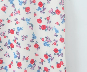 Detailed macro view of white floral fabric with red blue and purple floral embroidery