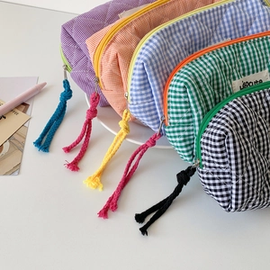 Flat lay of colorful quilted checkered pencil cases with decorative knot zippers on a tray
