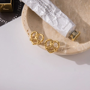 Detailed view of gold heart knot stud earrings resting on a stylish marble tray