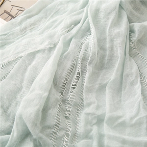 Detail of mint green scarf featuring crinkle texture and vertical hollow-out design