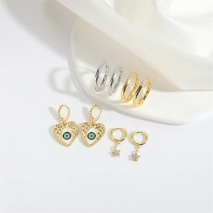 Evil eye heart and star charms with crystal hoop earrings set on white fabric