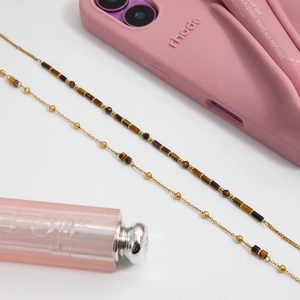 Detailed macro of golden chain necklace with tiger eye beads on elegant setting