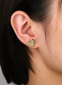 Close-up of elegant gold-plated heart stud earring worn on model earlobe