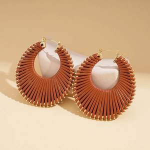 Detailed shot of large red-brown woven hoop earrings with elegant golden metal accents