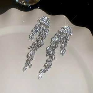 Close-up of silver long leaf tassel earrings with sparkling rhinestones on white plate
