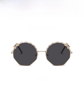 Détail de lunettes de soleil polygonales en métal doré avec nœud et verres gris