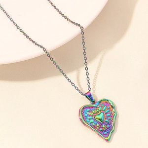Detailed close-up of rainbow heart pendant with 18k vacuum plating on textured background