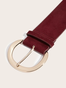 Détail d'une ceinture large en daim bordeaux avec une grande boucle dorée polie