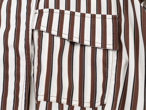 Detailed close-up of brown and white vertical stripe shirt fabric and pocket stitching