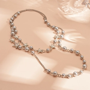 Multilayer long pearl necklace with silver star pendants on warm apricot background