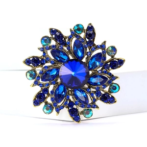 Detailed macro view of vintage gold alloy brooch with deep blue rhinestones and crystal leaves