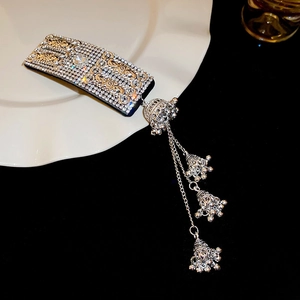 Detail of ethnic style velvet headband with rhinestone inlay and bell tassel charms