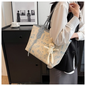 Dettaglio della borsa tote bianca con graffiti blu chiaro e ciondolo a coniglio