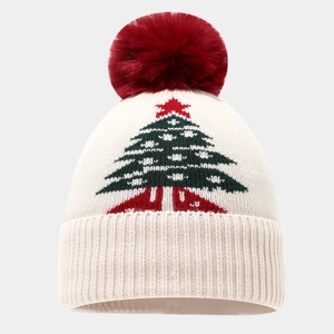 Detail der Weihnachtsstrickmütze mit rotem Bommel und festlichem grünen Baum-Muster