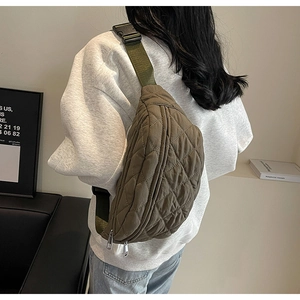 Detail of army green quilted nylon chest bag with adjustable strap shown on model's back