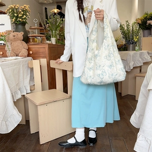 Close-up of white plush tote bag featuring blue butterfly prints in a cozy setting