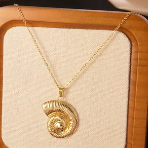 Detailed macro view of a gold nautilus seashell pendant necklace on a soft fabric display