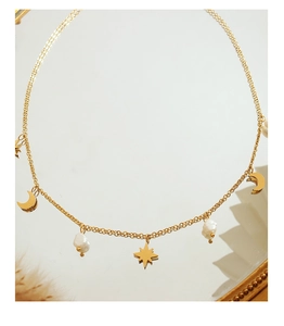 Detalle del collar dorado con colgantes de estrella y luna adornado con perlas naturales