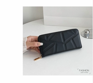 Detail of black long PU leather wallet with geometric quilting and gold zipper