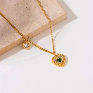 Detail of gold double heart pendant necklace with green and clear zircon stones