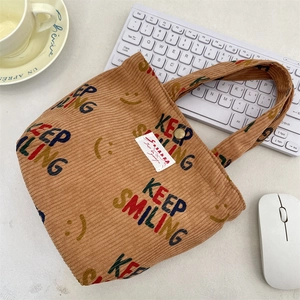 Detail view of corduroy handbag with KEEP SMILING embroidery and metal snap closure