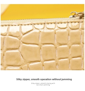 Macro detail of beige crocodile embossed leather with smooth golden zipper and stitching