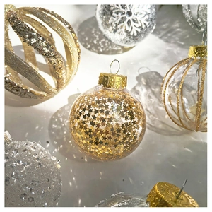 Detailed view of clear Christmas ornaments with golden sequins and hand-painted snowflakes