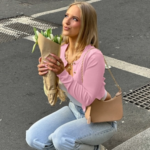 Détail du cardigan en maille rose à boutons dorés porté avec un jean dans un style urbain