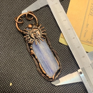 Detailopname van handgemaakte bronzen zonnehanger met blauwe kyaniet en schuifmaatmeting