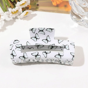 Detail of large acrylic hair claw clip with black butterfly print on white finish