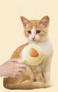 Detail view of yellow cat grooming brush removing loose fur from an orange tabby cat