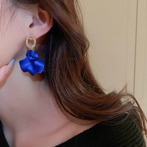 Close-up of matte royal blue petal drop earrings on model with golden metal hoops
