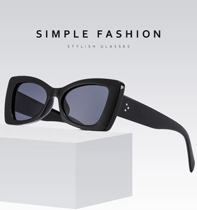Detail view of cat-eye sunglasses with thick black frames and metal rivet accents