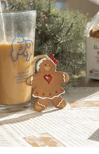 Détail d'un ornement bonhomme en pain d'épices avec texture biscuit et nœud rouge sur sapin
