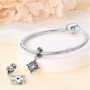 Close-up of silver star and snowflake charms with pink and blue gemstones on a bracelet