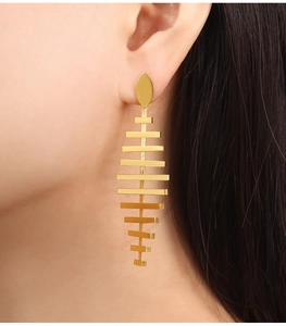 Detail view of 18K gold plated fishbone drop earrings worn by model in a close-up shot