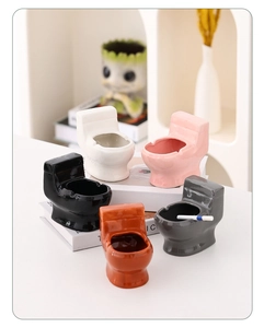 Detail of five toilet-shaped ceramic ashtrays in white, pink, black, gray and orange