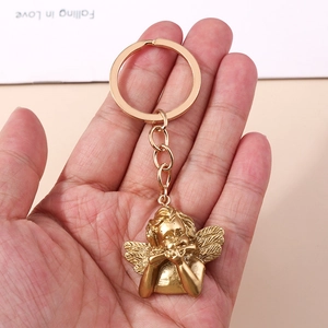 Detail of golden cupid angel keychain with wings playing flute on metal ring