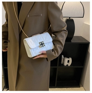 Close-up of a white quilted shoulder bag with a vintage black gemstone square buckle